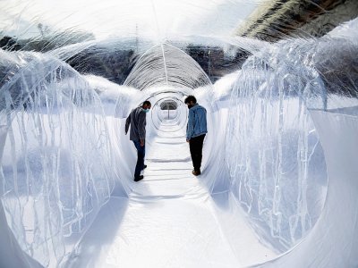 Deux hommes marchent dans un tunnel de plastique destiné à isoler les patients du covid le 16 février 2021 à Bogota - Juan BARRETO [AFP]