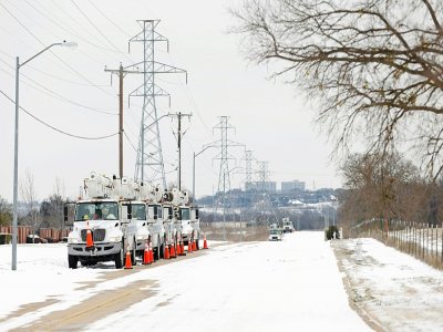 Des camions d'une compagnie d'électricité garés le long d'une route enneigée à Fort Worth, au Texas, le 16 février - Ron Jenkins [GETTY IMAGES NORTH AMERICA/AFP]