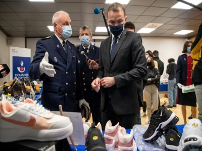 Le ministre des Comptes publics Olivier Dussopt regarde les produits de contrefaçon saisis par les douanes, le 22 février 2021 à l'aéroport de Roissy-Charles-de-Gaulle - BERTRAND GUAY [AFP]