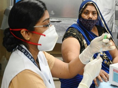 Une soignante se prépare à administrer le vaccin anti-Covid à une femme dans un hôpital de New Delhi le 1er mars 2021 - Sajjad HUSSAIN [AFP]