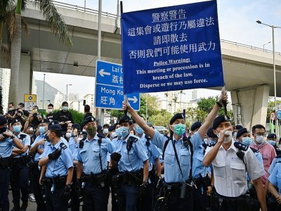 La police brandit des pancartes d'avertissement aux manifestants pro-démocratie rassemblés devant le tribunal de Kowloon, le 1er mars 2021 à Hong Kong - Peter PARKS [AFP]