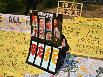 Un militant pro-démocratie devant le tribunal de Kowloon fait le salut à trois doigts, le 1er mars 2021 à Hong Kong - Peter PARKS [AFP]