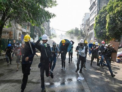 Des manifestants contre le coup d'Etat fuient les gaz lacrymogènes de la police, à Rangoun en Birmanie le 2 mars 2021 - STR [AFP]
