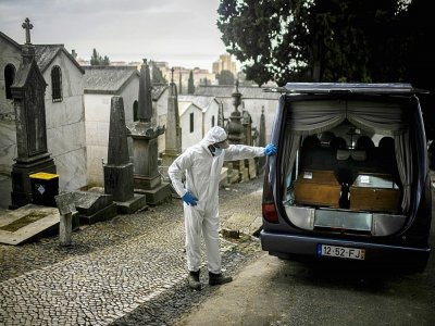 Un employé des pompes funèbres à côté de cercueils de victimes du Covid-19 dans un cimetière de Lisbonne, au Portugal, le 18 février 2021 - PATRICIA DE MELO MOREIRA [AFP]