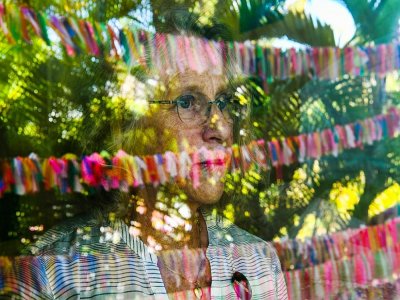 Cathy Tobias, 67 ans, regarde par sa fenêtre les milliers de rubans accrochés dans son jardin - CHANDAN KHANNA [AFP]