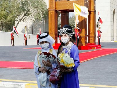 Des enfants irakiens en costume traditionnel arabe (G) et kurde (D) attendent l'arrivée du pape devant le palais présidentiel à Bagdad le 5 mars 2021 - Sabah ARAR [AFP]