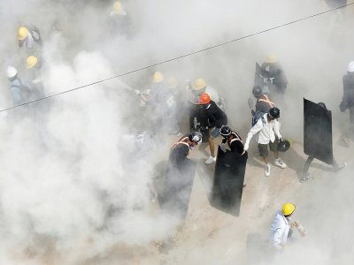 Des manifestants pris dans la fumée de gaz lacrymogènes envoyés par les forces de l'ordre et de gaz d'extincteurs utilisé par certains manifestants, à Rangoun, le 6 mars 2021 - STR [AFP]