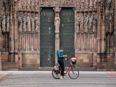 Une cycliste s'arrête pour consulter son téléphone, devant la cathédrale de Strasbourg, en mars 2020 - PATRICK HERTZOG [AFP/Archives]