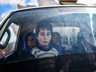 Un enfant syrien regarde depuis une voiture des civils en train de fuir la ville d'Afrine dans le nord-est de la Syrie, le 17 mars 2018 - BULENT KILIC [AFP/Archives]