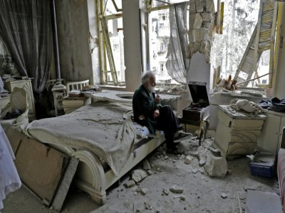 Un Syrien fume dans les ruines de sa maison en écoutant un disque sur un gramophone, à Alep, en Syrie,  le 9 mars 2017 - JOSEPH EID [AFP/Archives]