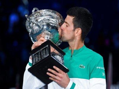 Le Serbe Novak Djokovic embrasse le trophée de l'Open d'Australie, après sa victoire en finale, le 21 février 2021 à Melbourne - William WEST [AFP/Archives]