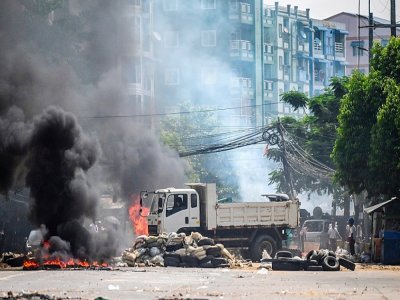 Des policiers mettent le feu à une barricade dans une rue de Rangoun le 19 mars 2021 - STR [AFP]