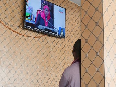 Un habitant du quartier de Kawe Kanisani à Dar-es-Salaam regarde la prestation de serment de la nouvelle présidente tanzanienne Samia Suluhu Hassan, le 19 mars 2021 - - [AFP]