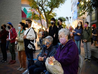 Des personnes portant des masques tiennent des bougies lors d'un hommage aux victimes du coronavirus  le 20 mars 2021 dans le quartier de Little Tokyo à Los Angeles, Californie - Patrick T. FALLON [AFP]