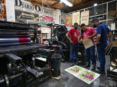 Le maître imprimeur Olmedo Franco (g) et des collaborateurs vérifient une affiche imprimée à La Linterna, le 2 mars 2021 à Cali, en Colombie - Luis ROBAYO [AFP]