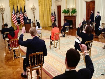 Des journalistes lèvent le bras pour poser une question au président américain Joe Biden après la première conférence de presse de son mandat, le 25 mars 2021 à Washington - Jim WATSON [AFP]