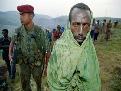 Un réfugié tutsi attend sous la pluie près d'un parachutiste français le 29 juin 1994 dans le camp de réfugiés de Nyarushishi où 8.000 Tutsi ont été rassemblés sous la protection des forces françaises - Pascal GUYOT [AFP/Archives]