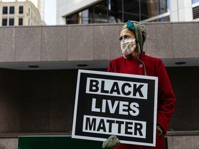 Une femme manifeste le 31 mars 2021 avec un panneau "Black Lives Matter" (les vies noires comptent) devant le tribunal de Minneapolis où se tient le procès du policier blanc accusé du meurtre de George Floyd - Kerem Yucel [AFP]