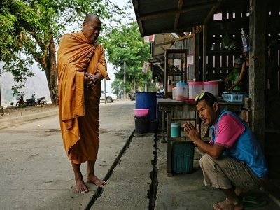Un moine bouddhiste bénit un migrant birman de l'ethnie Karen dans le village frontalier de Mae Sam Laep en Thaïlande le 31 mars 2021 - Lillian SUWANRUMPHA [AFP]
