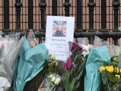 Une photo du prince Philip au milieu des fleurs déposées devant les grilles du palais de Buckhingham au lendemain de son décès, le 10 avril 2021 à Londres - Glyn KIRK [AFP]