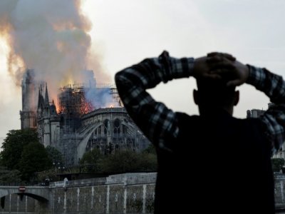 Un passant regarde Notre-Dame en flammes le 15 avril 2019 - Geoffroy VAN DER HASSELT [AFP/Archives]