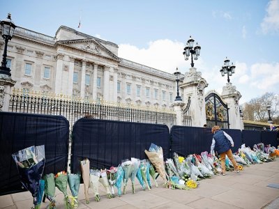 Des fleurs sont déposés le long de la grille du palais de Buckingham, le 11 avril 2021 deux jours après l'annonce du décès du prince Philip - Tolga Akmen [AFP]