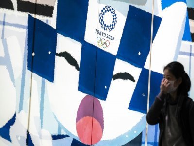 Une Japonaise portant un masque de protection contre le coronavirus avance devant le logo ds Jeux de Tokyo 2020 dans la capitale, le 13 avril 2021 - Charly TRIBALLEAU [AFP]