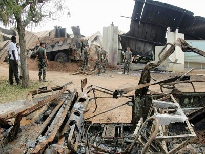 Des soldats français nettoient les décombres tombés sur un blindé après le bombardement du lycée Descartes à Bouaké, en Côte d'Ivoire, qui leur servait de base, le 10 novembre 2004 - Philippe DESMAZES [AFP/Archives]