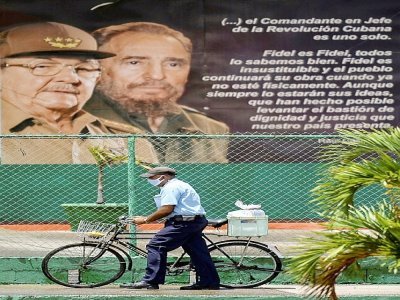 Un homme passe devant une affiche montrant les ex-présidents cubains Fidel et Raul Castro, à La Havane le 13 avril 2021 - YAMIL LAGE [AFP]