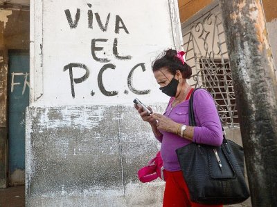 Une Cubaine passe devant un graffiti disant "Vive le PCC", le Parti communiste cubain, à La Havane le 6 avril 2021 - YAMIL LAGE [AFP]