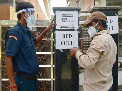 Un agent de sécurité affiche un message prévenant que plus aucun lit n'est disponible, dans un hôpital privé d'Allahabad (Inde) le 22 avril 2021 - Sanjay KANOJIA [AFP]