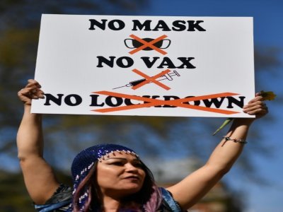Une manifestante et sa banderolle "Pas de masque Pas de vaccins Pas de confinement" le 24 avril 2021 à Londres - Ben STANSALL [AFP]