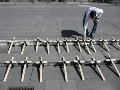 Un membre d'une ONG dépose des croix en bois sur les marches de la cathédrale de Santiago, le 25 avril 2021, en hommage aux personnes décédées du Covid-19 au Chili - Martin BERNETTI [AFP]