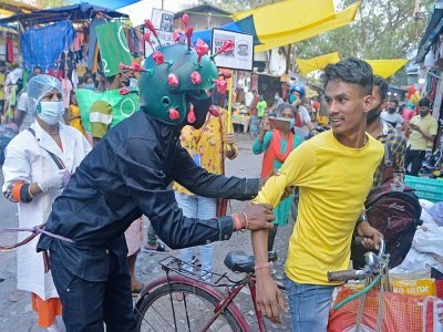Un membre d'une ONG vêtu d'un costume ressemblant au virus Covid-19 informe la population de mesures sanitaires à observer, à Siliguri, en Inde, le 25 avril 2021 - DIPTENDU DUTTA [AFP]