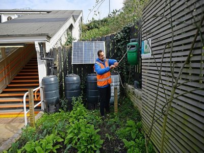 Agamemnon Otero, directeur du projet Energy Garden, prépare l'arrosage d'un potager près de la station Brondesbury Park de l'Overground, le 24 mars 2021 à Londres - JUSTIN TALLIS [AFP]