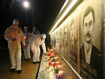 Des employés de la centrale de Tchernobyl allument des bougies et déposent des fleurs devant le monument à la mémoire des victimes de la catastrophe, à Slavutych, la ville où le personnel du site vivait, à 50 km du site, le 25 avril 2021 - Sergei SUPINSKY [AFP]