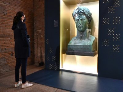 Une visiteuse admire un bronze "Buste de Napoléon 1er, empereur" du sculpteur italien Lorenzo Bartolini, lors de l'exposition "Napoléon et le mythe de Rome" au Musée des marchés de Trajan, le 11 mars 2021 à Rome - ANDREAS SOLARO [AFP]