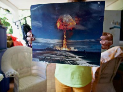 Un habitant de Rikitea, sur l'île de Mangareva, dans l'archipel des Gambier, montre le 26 avril 2021 une photo du champignon nucléaire lors d'un essai à Moruroa - Suliane FAVENNEC [AFP]