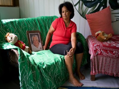 Maria Mahaa, 46 ans, pose le 24 avril 2021 dans sa maison à Taku, en Polynésie française, avec l'une des dernières photographies de son père, mort d'un cancer de la thyroïde - Suliane FAVENNEC [AFP]