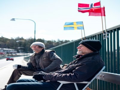 Pontus Berglund (g) et son frère jumeau Ola bavardent, l'un en Suède, l'autre en Norvège, sur le pont reliant les deux pays, le 1er mai 2021 à Svinesund - Petter BERNTSEN [AFP]