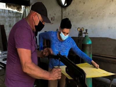 Le carrossier Pedro Manso (g) aide son apprentie Lemaydi Madrigal (d) dans son atelier de Placetas, dans la province de Villa Clara, le 24 avril 2021 à Cuba - ADALBERTO ROQUE [AFP]