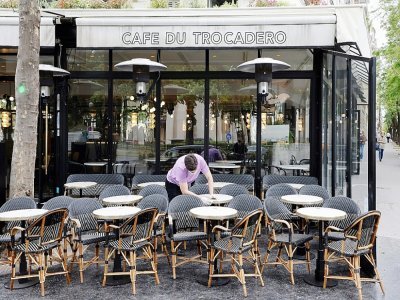 Un employé du "café du Trocadero" à Paris, nettoie les tables de la terrasse, le 11 mais 2021, une semaine avant la réouverture prévue des terrasses - Ludovic MARIN [AFP/Archives]