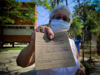 Une femme montre sa carte de vaccination après avoir reçu une injection du candidat-vaccin cubain Abdala contre le Covid-19, le 12 mai 2021 à La Havane - YAMIL LAGE [AFP]