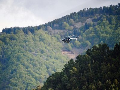 Un hélicoptère survole une zone forestière des Cévennes, le 12 mai 2021, à la recherche du fugitif qui a tué deux personnes - CLEMENT MAHOUDEAU [AFP]