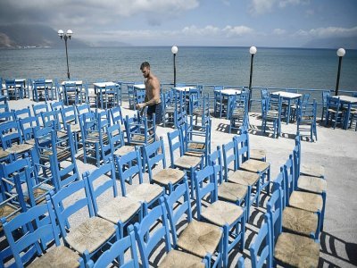 Un employé prépare l'installation d'une terrasse à Kissamos, dans le nord-ouest de la Crète, le 13 mai 2021 - Louisa GOULIAMAKI [AFP]
