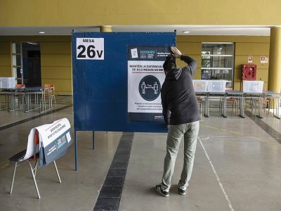 Pose d'une affiche sur un isoloir, dans un bureau de vote à Santiago du Chili, le 14 mai 2021 - Martin BERNETTI [AFP]