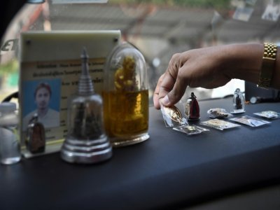 Le chauffeur de taxi Wasan Sukjit dispose des amulettes sur le tableau de bord de sa voiture, le 3 mars 2021 à Bangkok - Lillian SUWANRUMPHA [AFP]