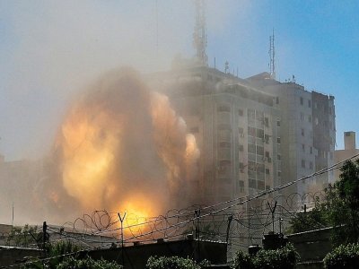 Une boule de feu jaillit d'un bâtiment qui abritait les locaux de médias internationaux, pulvérisé par une frappe israélienne, le 15 mai 2021 à Gaza - MOHAMMED ABED [AFP]