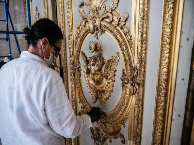 Un employé du Chateau de Versailles nettoie une porte le 17 mai 2021, avant son ouverture le 19 mai, après l'allègement en France des restrictions sanitaire dues à l'épidémie de Covid-19. - Martin BUREAU [AFP]