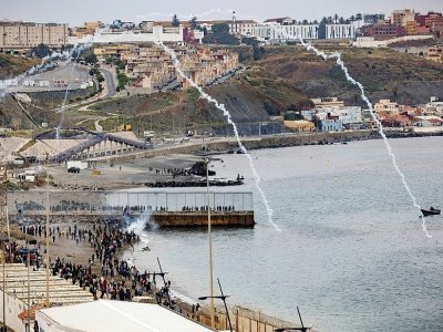 Les forces de sécurité espagnoles lancent du gaz lacrymogène pour tenter de repousser les migrants qui traversent la frontière entre le Maroc et l'enclave de Ceuta le 18 mai 2021 - FADEL SENNA [AFP]